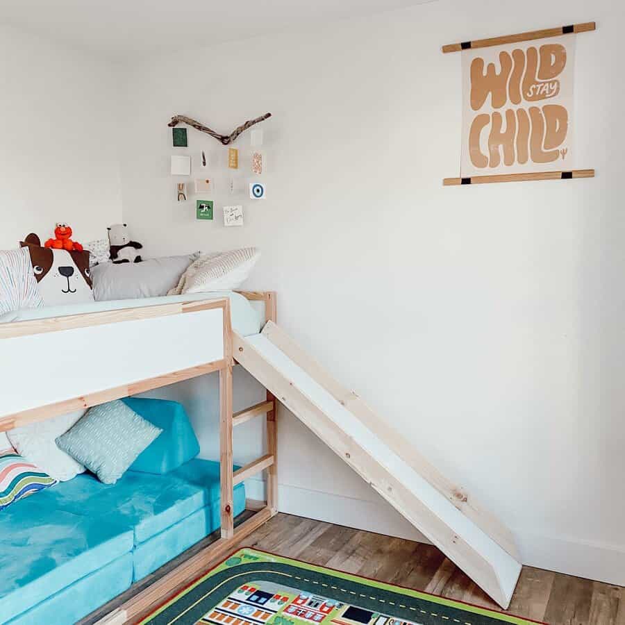 Children's room with loft bed, slide, stuffed animals, books, and a "Stay Wild Child" poster; floor mat with road design