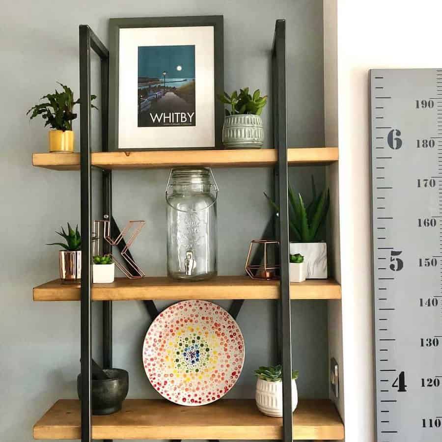 Wooden shelves with plants, art, a large jar, and a colorful plate; a height chart is on the wall