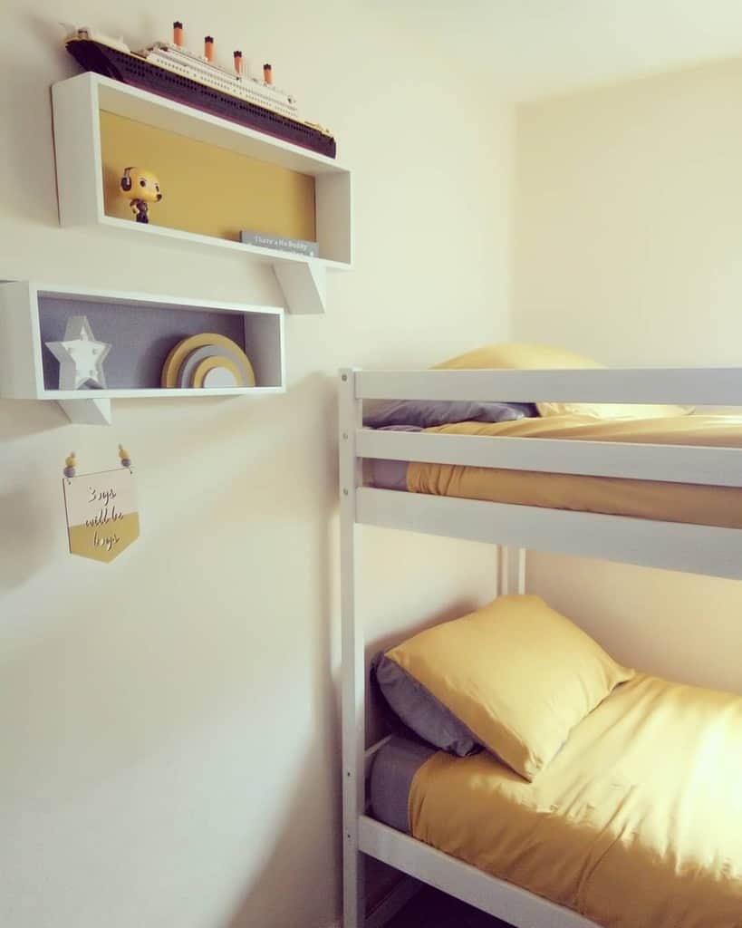 Cozy bedroom with a white bunk bed, yellow bedding, and shelves holding a model ship, a toy, and decorations