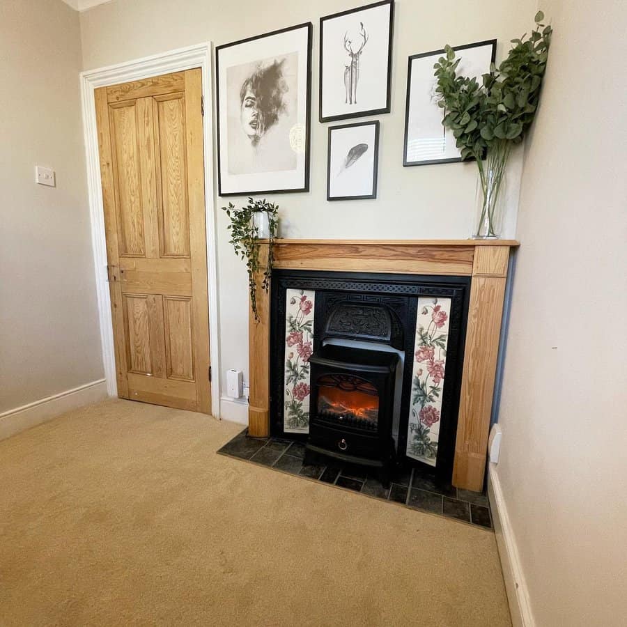 A modern fireplace with floral tiles, framed artwork on the wall, and greenery accents, creating a minimalist yet cozy look