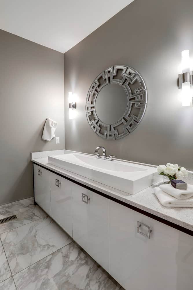 Modern bathroom with a rectangular sink, large decorative mirror, and elegant lighting fixtures on a marble floor