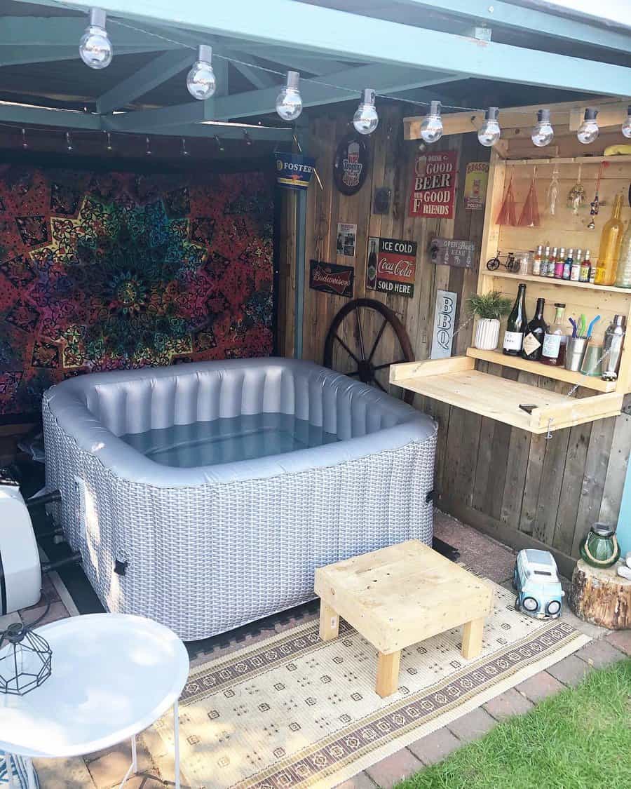 Cozy backyard retreat with a hot tub, rustic bar setup, string lights, and a boho tapestry, perfect for relaxation and entertaining