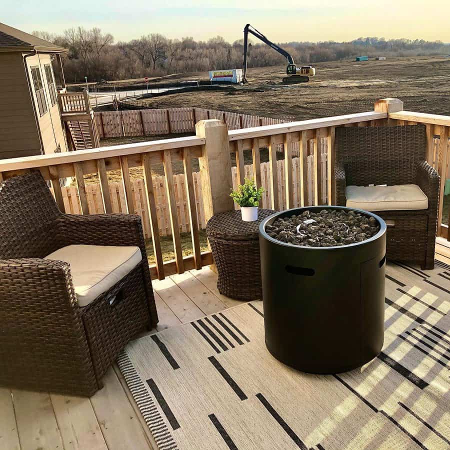 Cozy outdoor deck with wicker chairs, a round fire pit table, and a striped rug