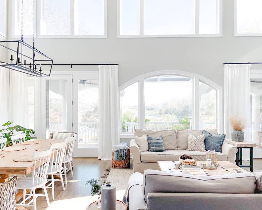 Bright, airy living room with large windows, light furniture, and a dining table.