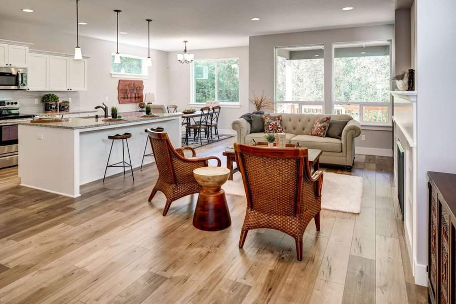 Open-concept living area with kitchen, dining, and seating with natural wood flooring.