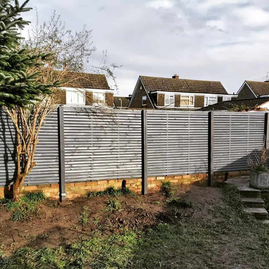 Grey horizontal fence with brick base in a garden setting