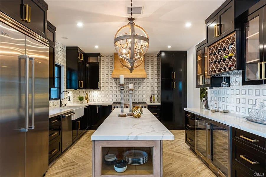 Modern kitchen with an island, chandelier, marble countertops, and stainless appliances