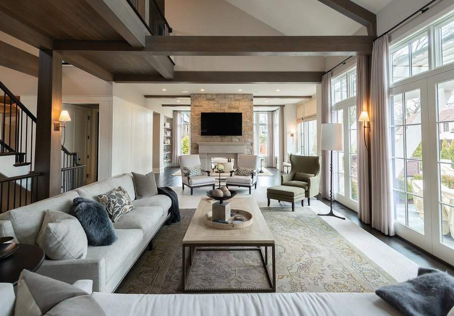 Spacious living room with large windows, cozy seating, a fireplace, and a TV mounted above; neutral tones and plush decor