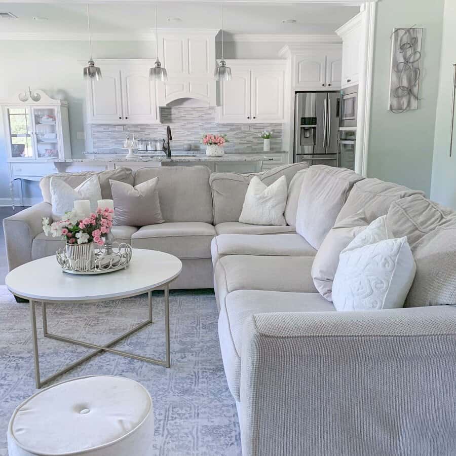 Bright open-concept living room and kitchen with a soft neutral palette, cozy sectional, and elegant farmhouse-style decor