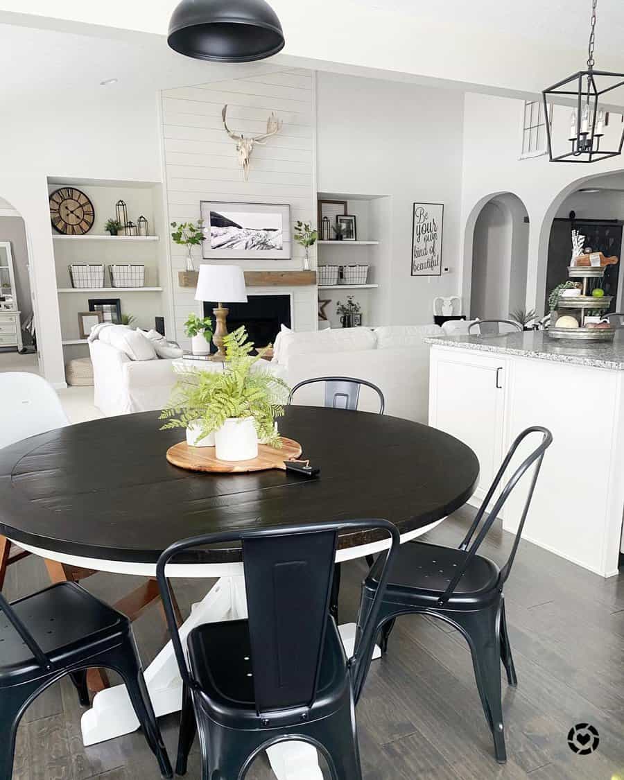 Modern kitchen-living area with black table, metal chairs, open shelves, and decor in white and gray tones dominate the room