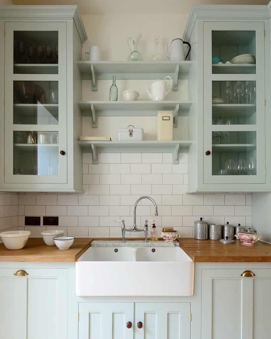 Charming farmhouse kitchen with pastel green cabinets, open shelves, a farmhouse sink, and a subway tile backsplash for a cozy feel