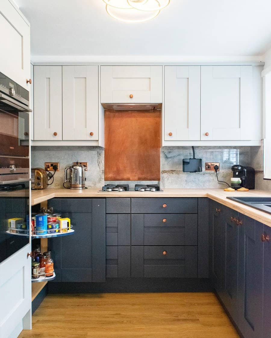 Stylish small kitchen with two-tone cabinets, copper backsplash, wooden countertops, and a pull-out pantry for smart storage solutions