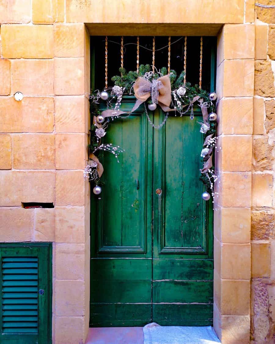 A green wooden door adorned with a festive garland and bow hanging above it