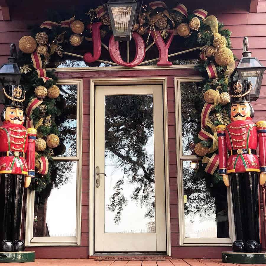 Holiday-decorated door with "JOY" sign, wreath, and two nutcracker figures