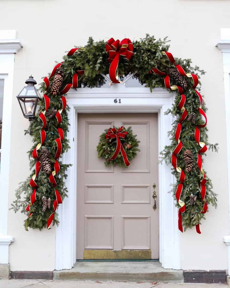 Festive holiday door with red ribbons, pinecones, and greenery arch for decoration