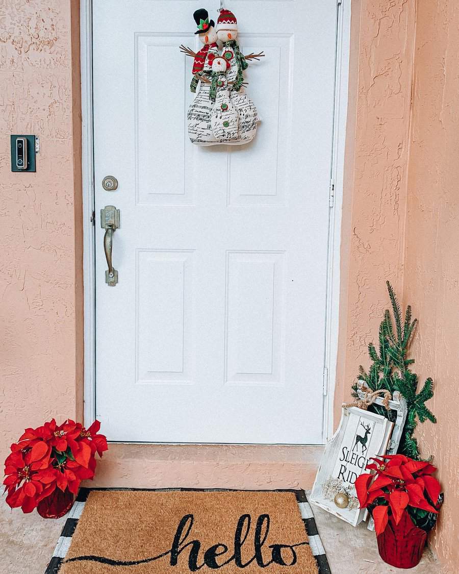 Decorated front door with winter wreath, poinsettias, and "hello" doormat