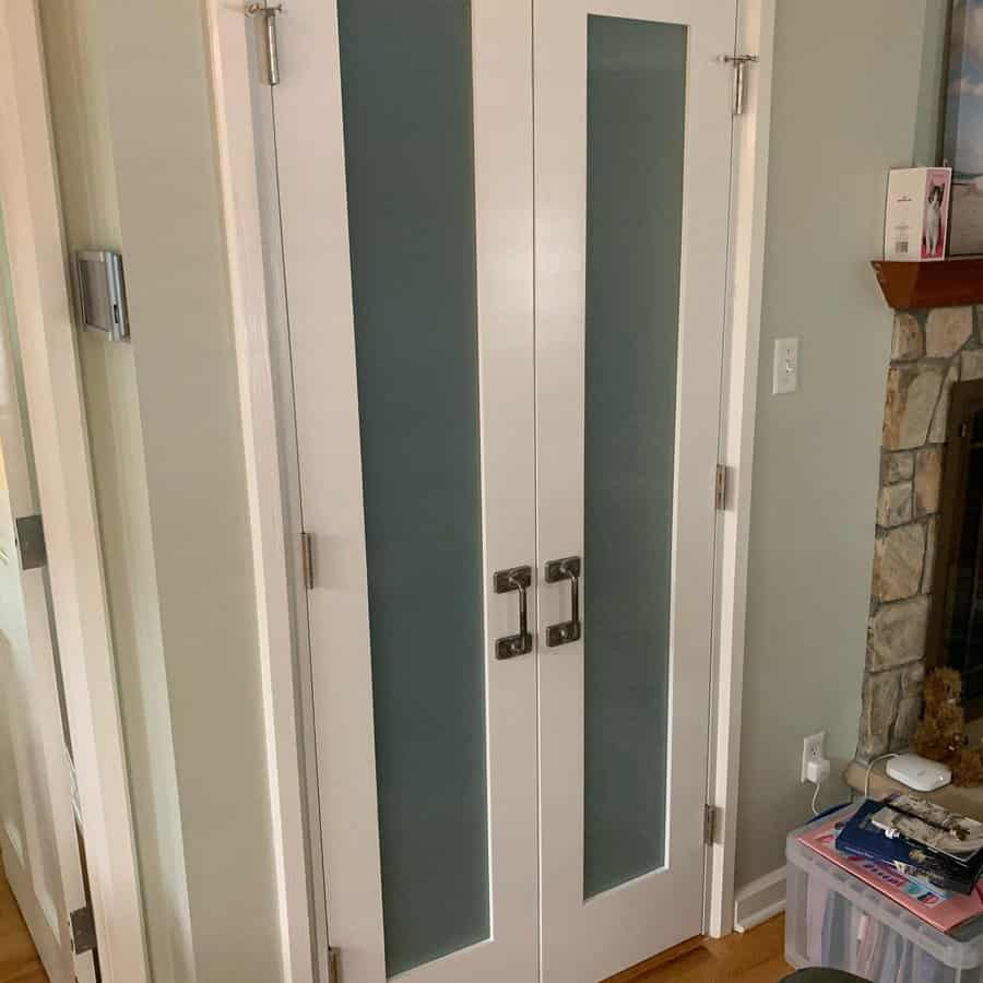 Sleek white double closet doors with frosted glass panels and modern metal handles add a contemporary touch to this cozy living space