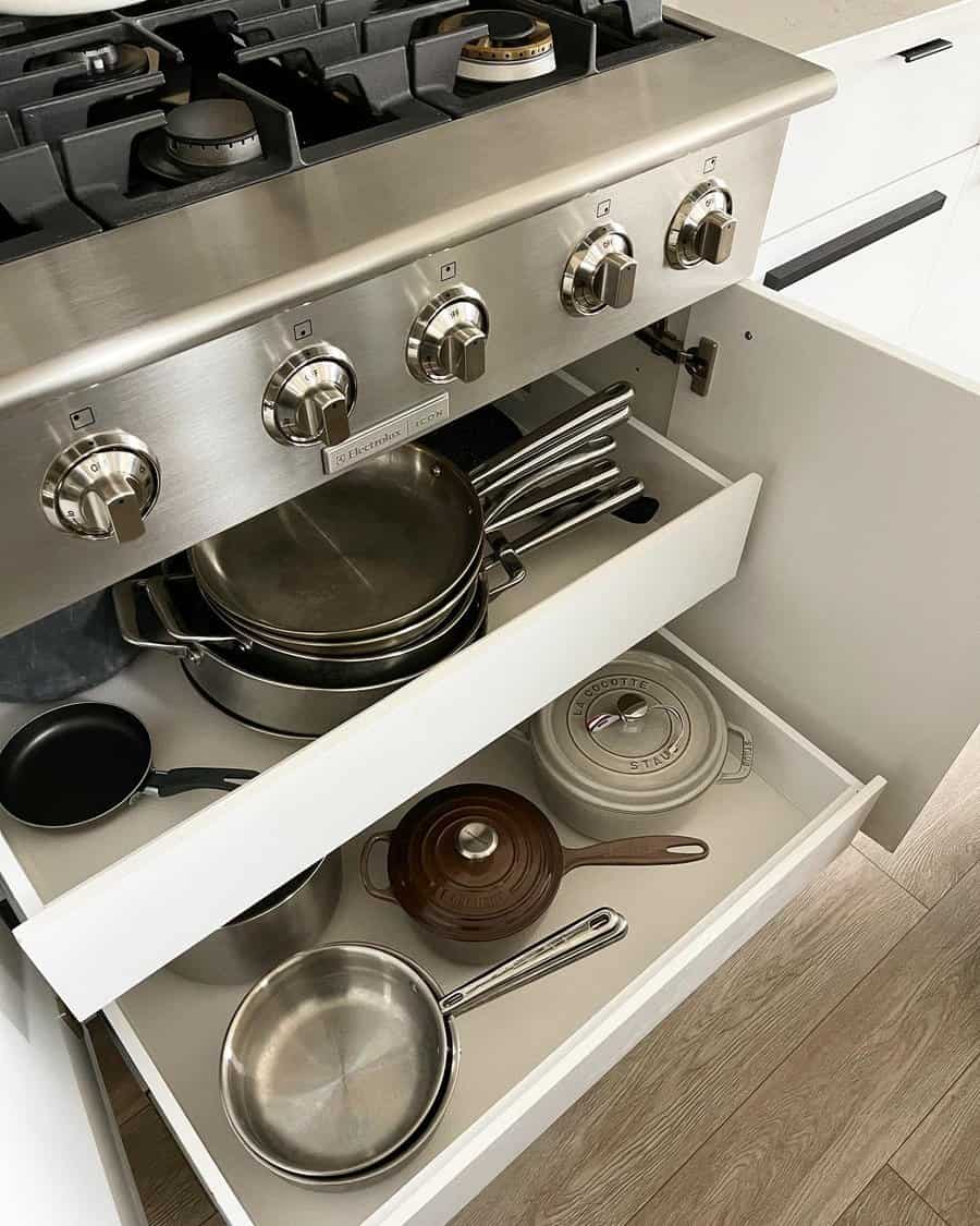 Modern kitchen with pull-out drawers under the stove, neatly storing pots, pans, and cast iron cookware for efficient organization