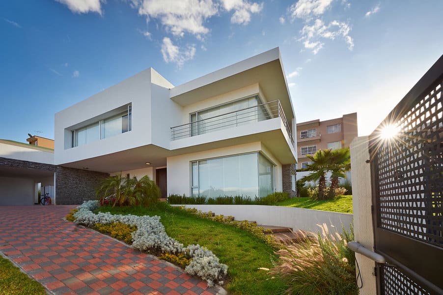 Modern white home with garden and brick driveway