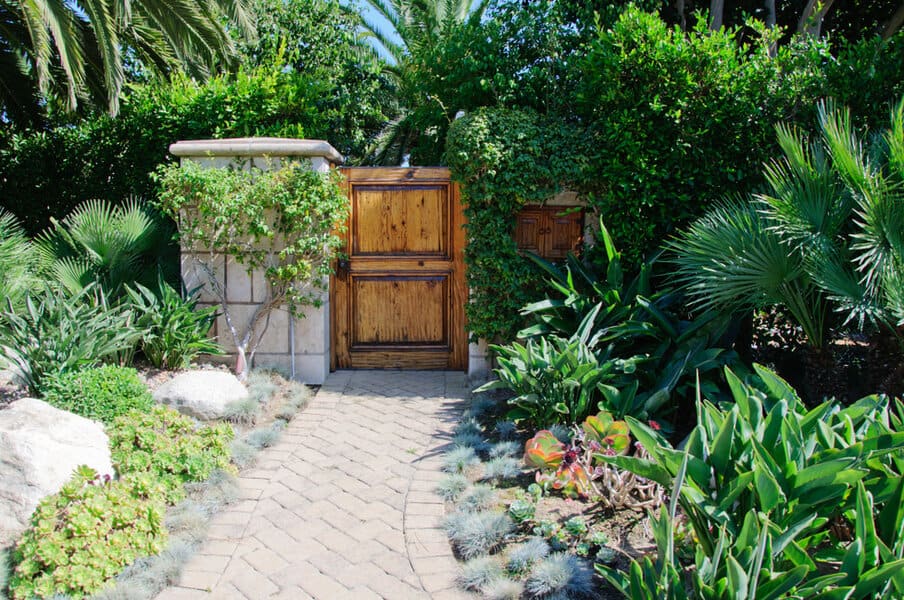 Tropical garden with wooden gate and stone path
