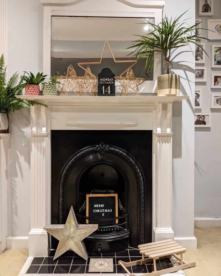 A festive fireplace mantel adorned with Christmas stars, plants, a holiday sign, and a mirror, creating a warm and welcoming seasonal look