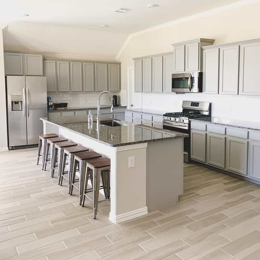 Spacious kitchen with gray cabinets and herringbone floor