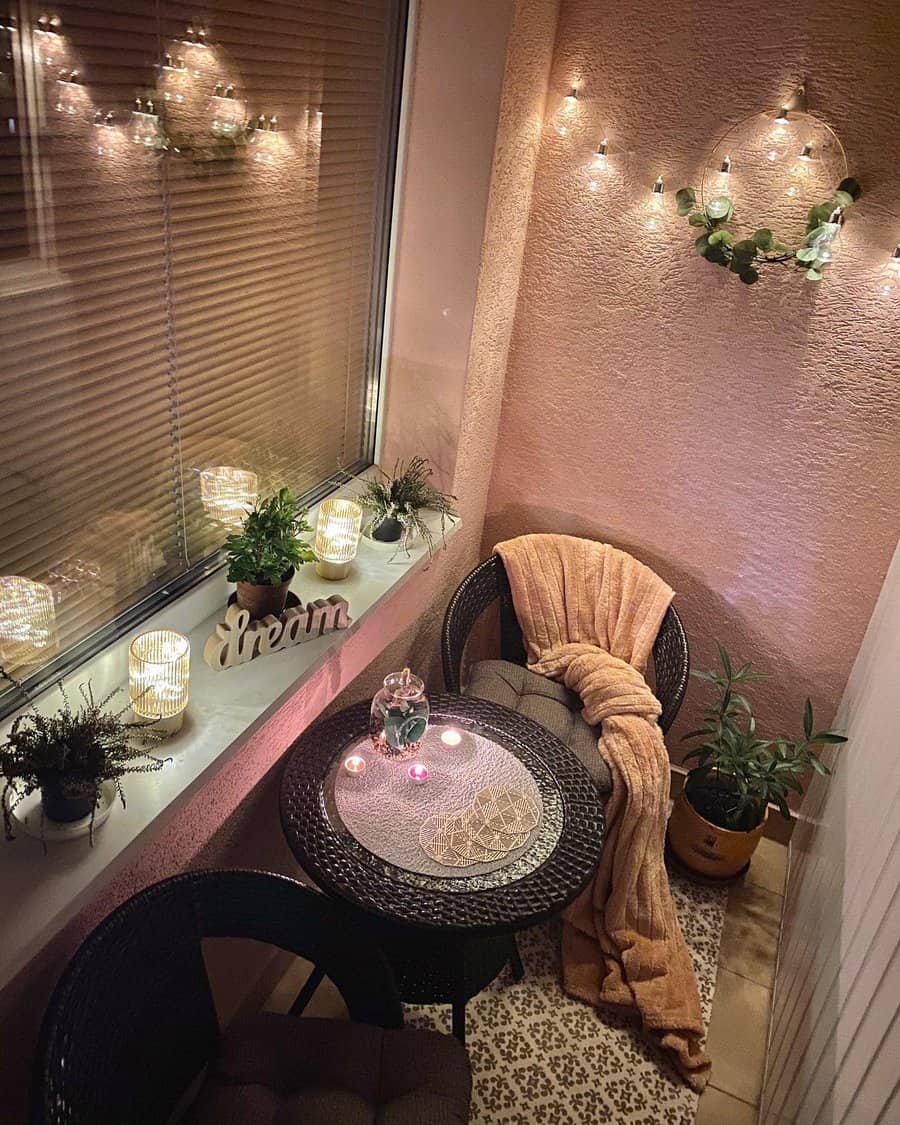 Cozy enclosed balcony with warm string lights, a bistro table set, soft blankets, candles, potted plants, and a relaxing ambiance