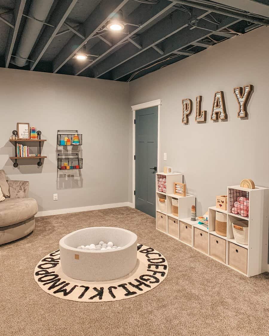 Charming basement playroom with an open ceiling, cozy carpet, organized toy storage, and a playful ball pit for a fun and inviting space.