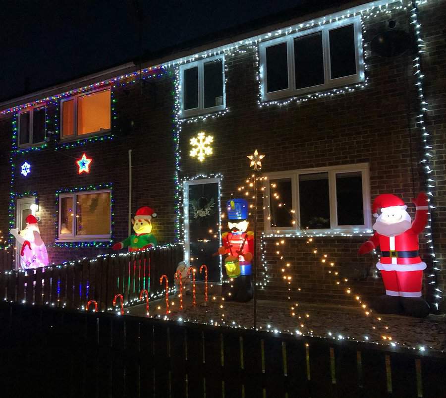 House decorated with festive lights, featuring inflatable Santa, snowman, nutcracker, and candy canes