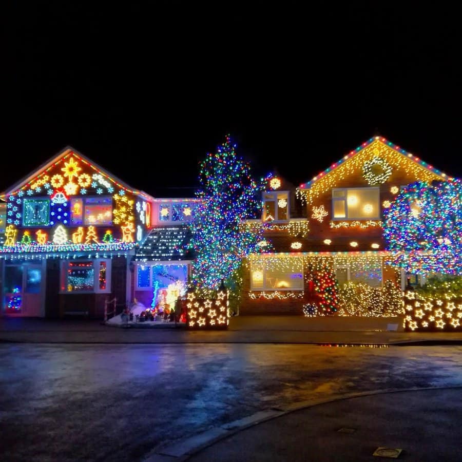 House decorated with colorful Christmas lights, featuring stars, snowflakes, and illuminated trees, glowing brightly at night