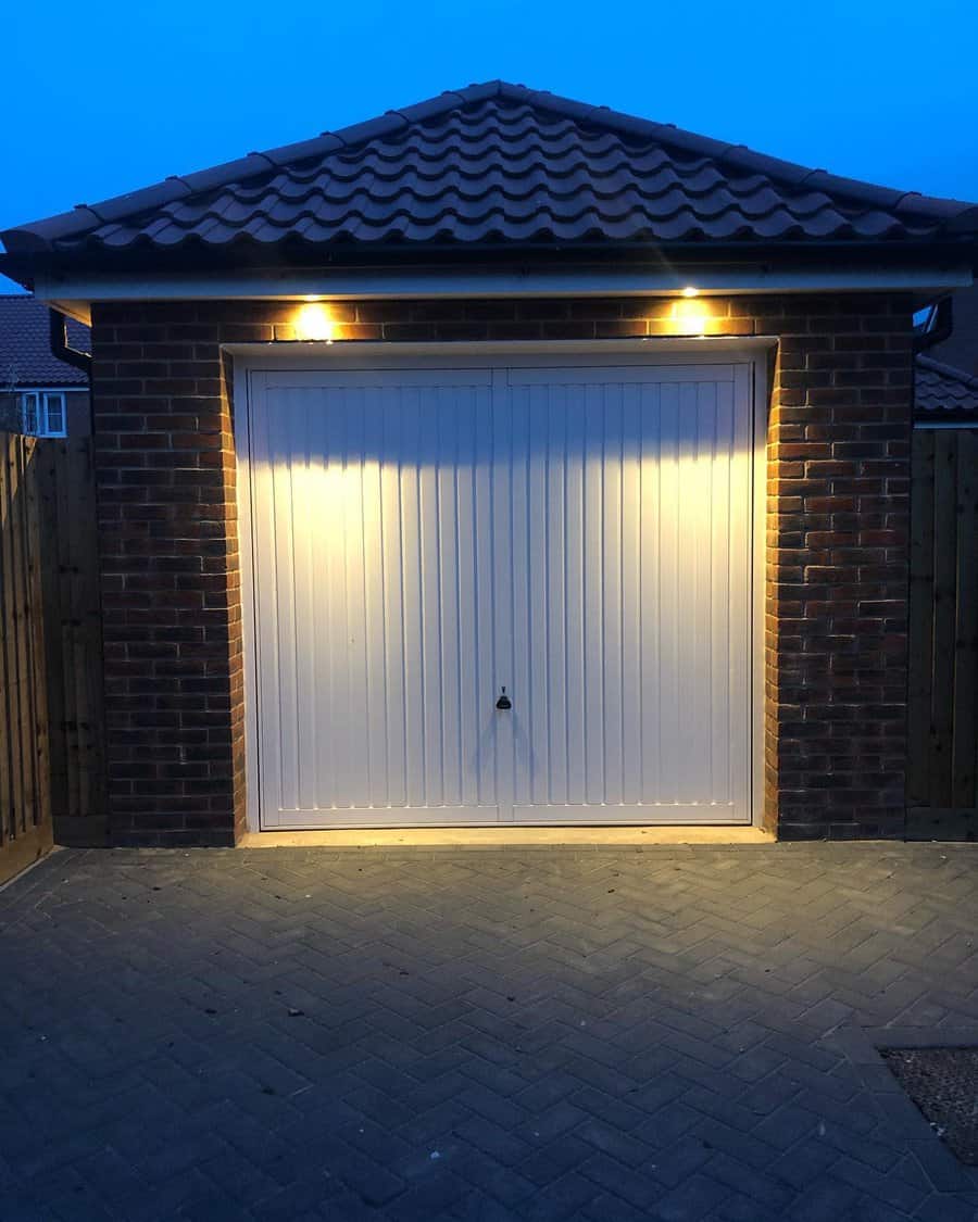 Garage door lit by overhead lights at dusk