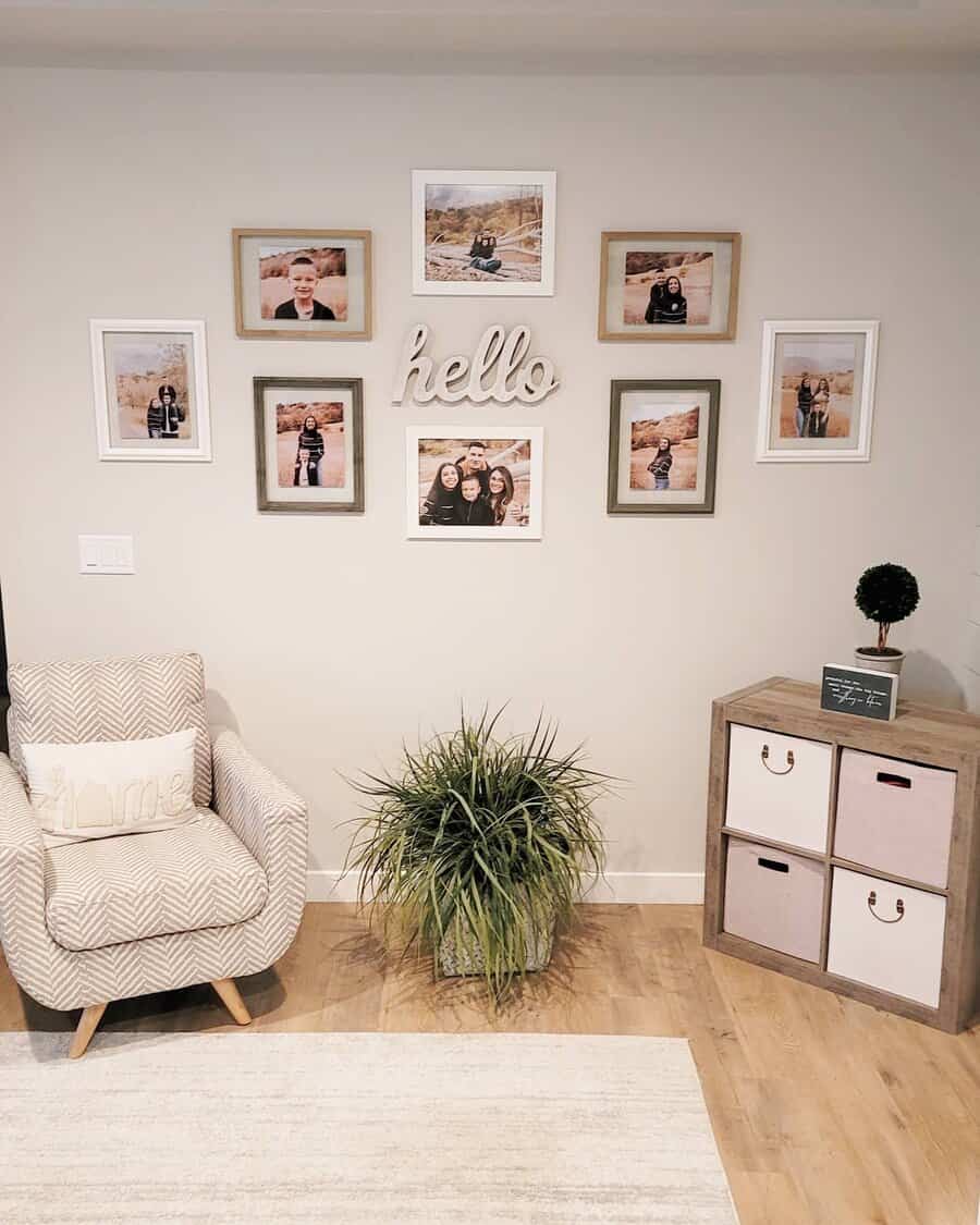 Cozy corner with framed photos on a wall, a "hello" sign, an armchair, a plant, and a small cabinet with storage cubes