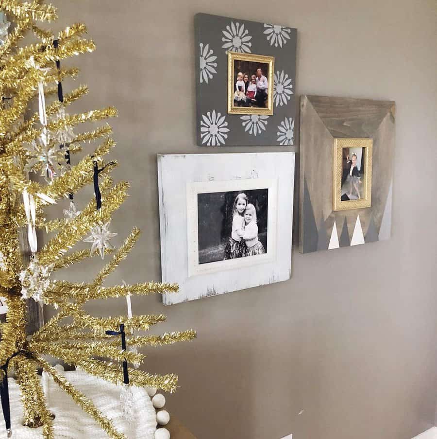 Wall with family photos in decorative frames; a small gold tinsel Christmas tree with snowflake ornaments is in the foreground