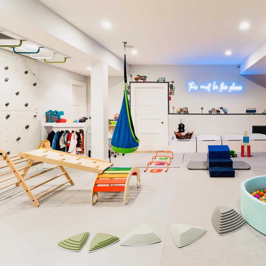 Bright and playful basement with a climbing wall, hanging swing, ball pit, and interactive play zones for an engaging kids' activity space.