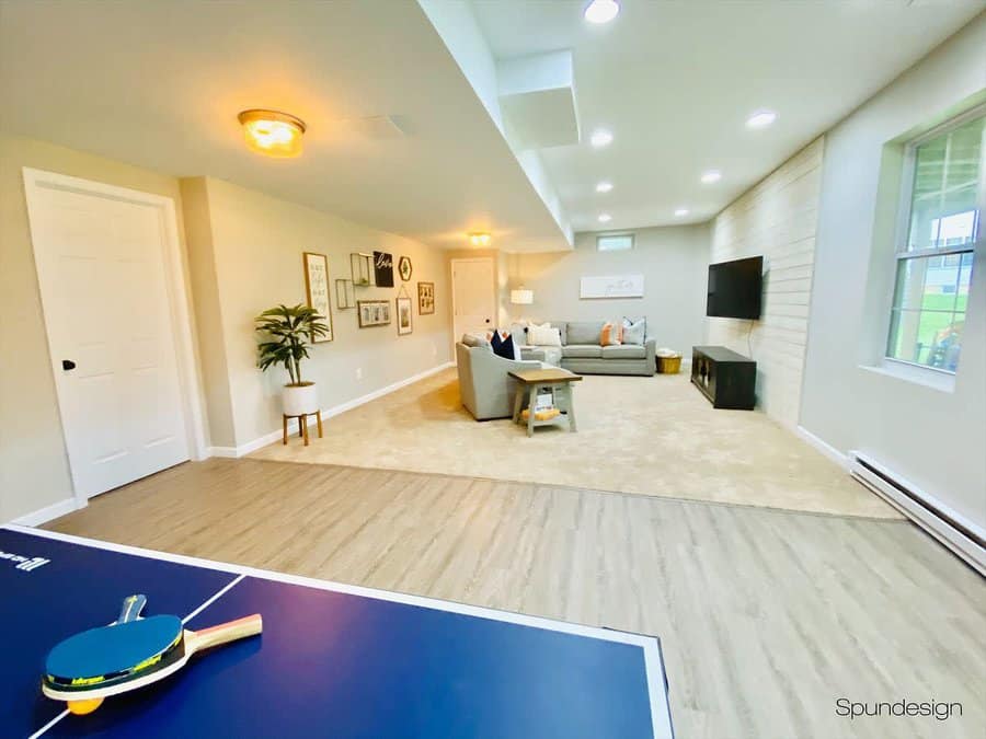 Bright and spacious basement family room with a cozy seating area, shiplap accent wall, and a ping pong table for entertainment and relaxation.