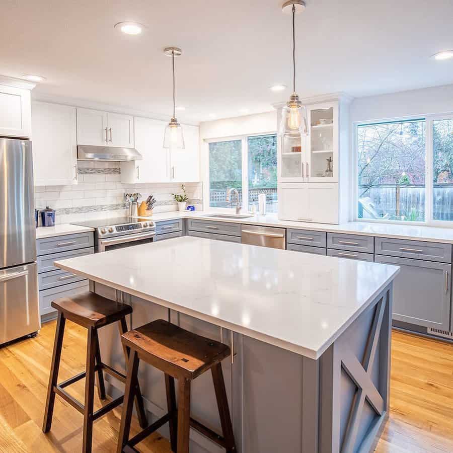 Bright farmhouse kitchen with a large gray island breakfast bar, white quartz countertops, wooden barstools, and pendant lighting for a modern touch