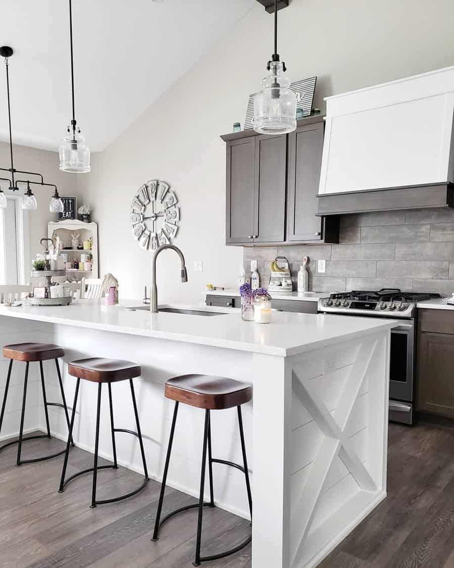 Modern farmhouse kitchen with a white shiplap island breakfast bar, wooden barstools, glass pendant lights, and dark cabinetry for contrast