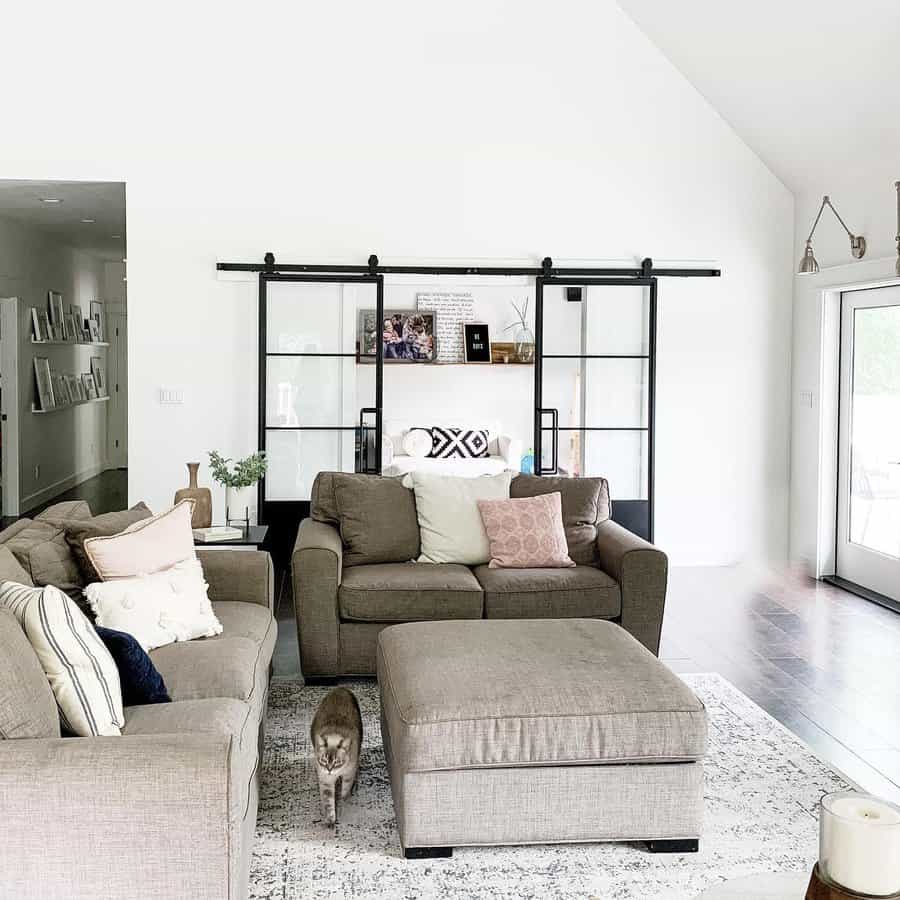 Modern living room with gray sofas, an ottoman, and black sliding doors.