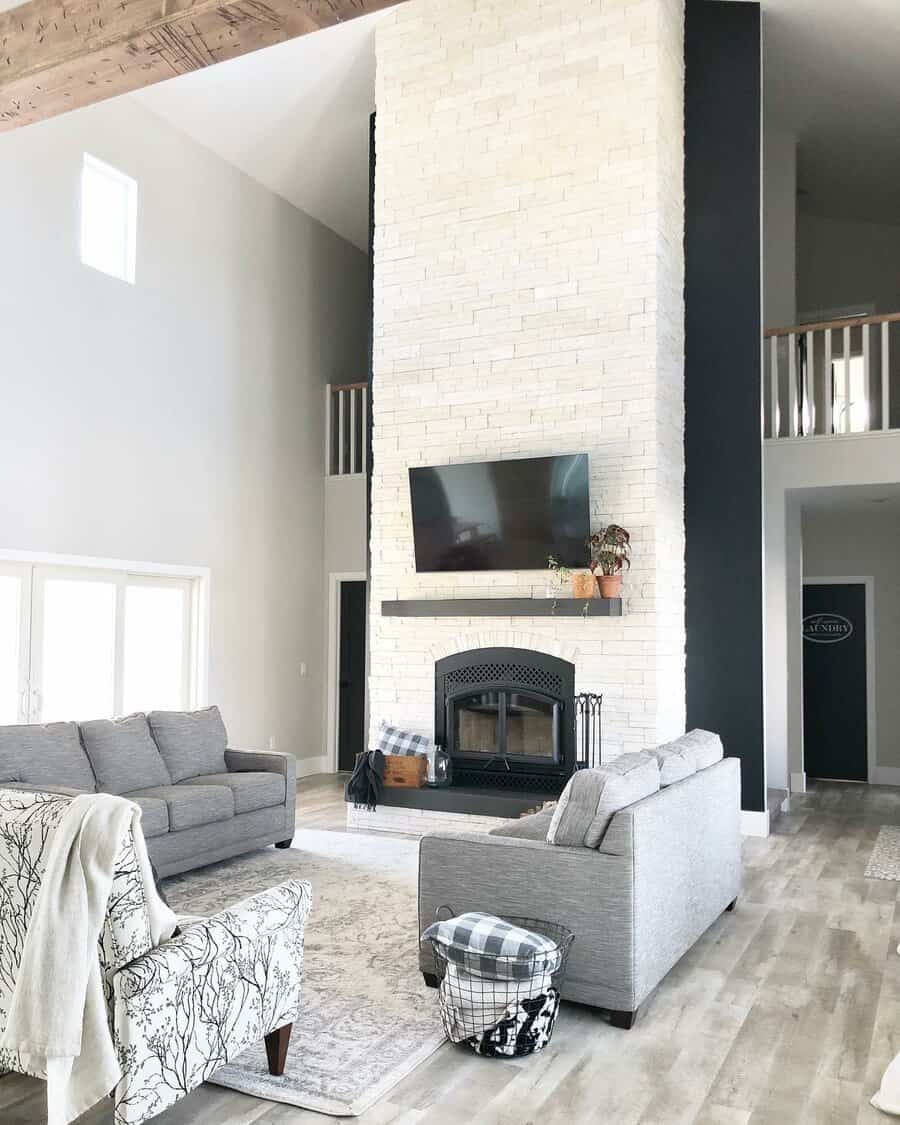 Modern living room with high ceiling, fireplace, and TV mounted above it.