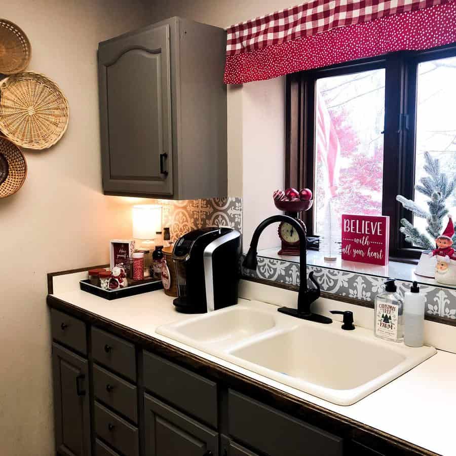 Cozy kitchen with a cream double sink, matte black faucet, festive red accents, and gingham valance adding a charming country touch