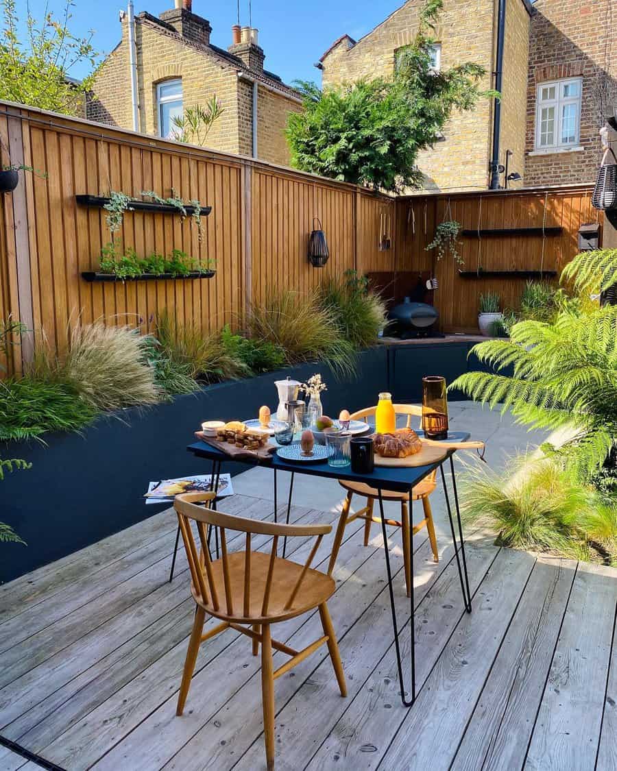 Stylish backyard with a wooden fence, floating plant shelves, lush greenery, a modern dining table, and a cozy breakfast setup on a deck