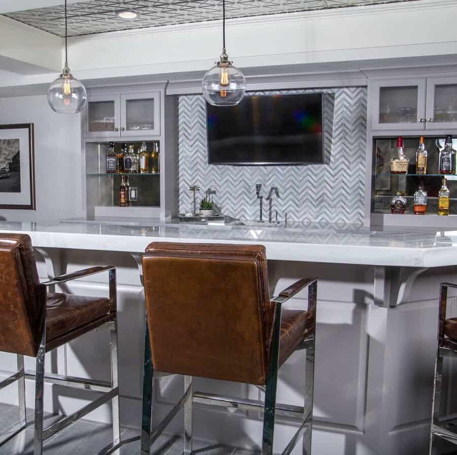 Sophisticated bar with chevron backsplash and leather stools