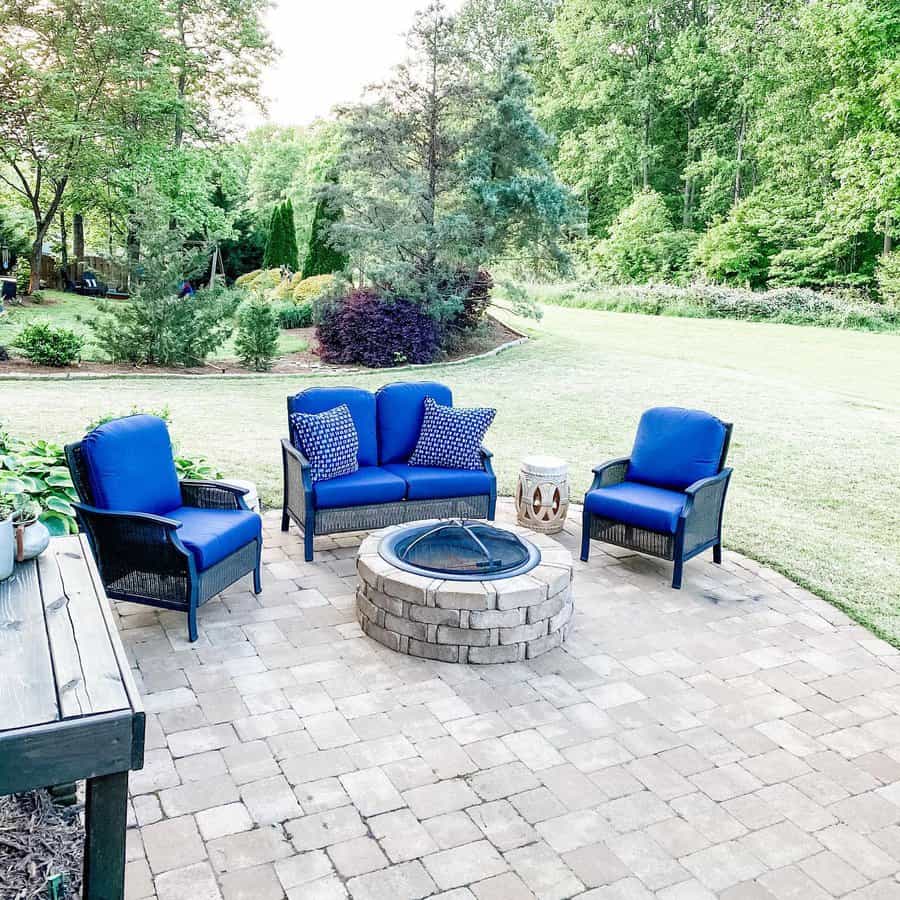 Patio with fire pit and blue chairs in a lush garden setting