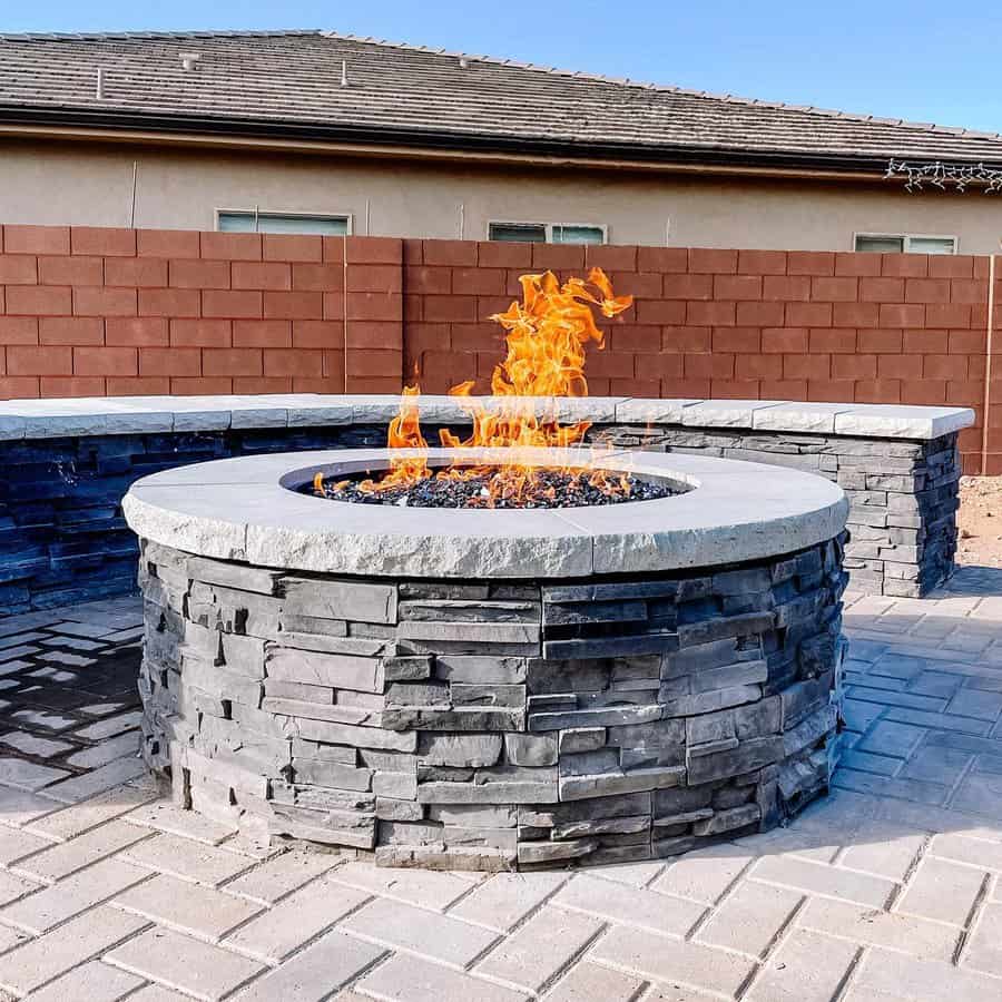 Circular stone fire pit with flames on patio