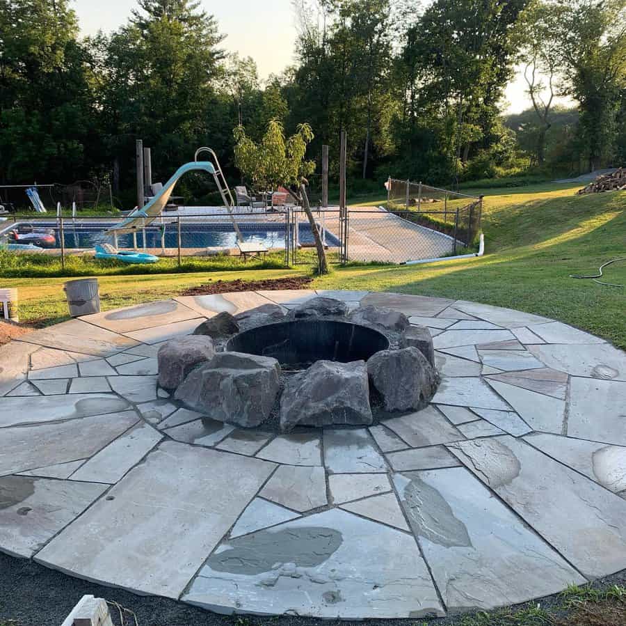 Stone patio with fire pit and pool in background