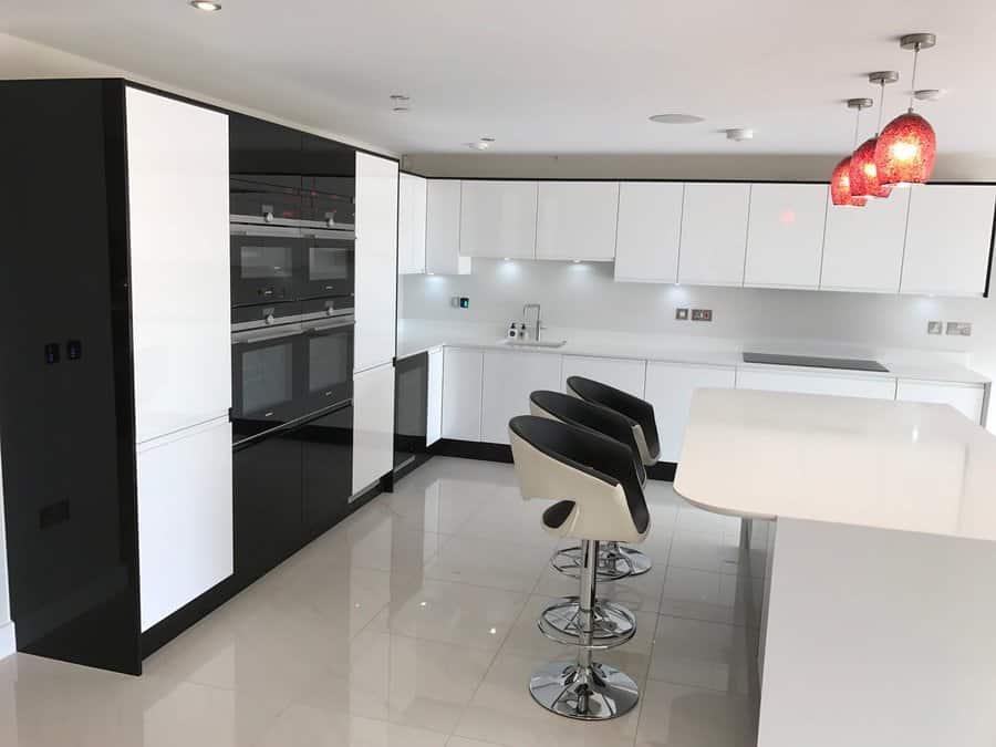 Glossy white tile flooring enhances this sleek modern kitchen, reflecting light to create a spacious and sophisticated look with black and white contrasts