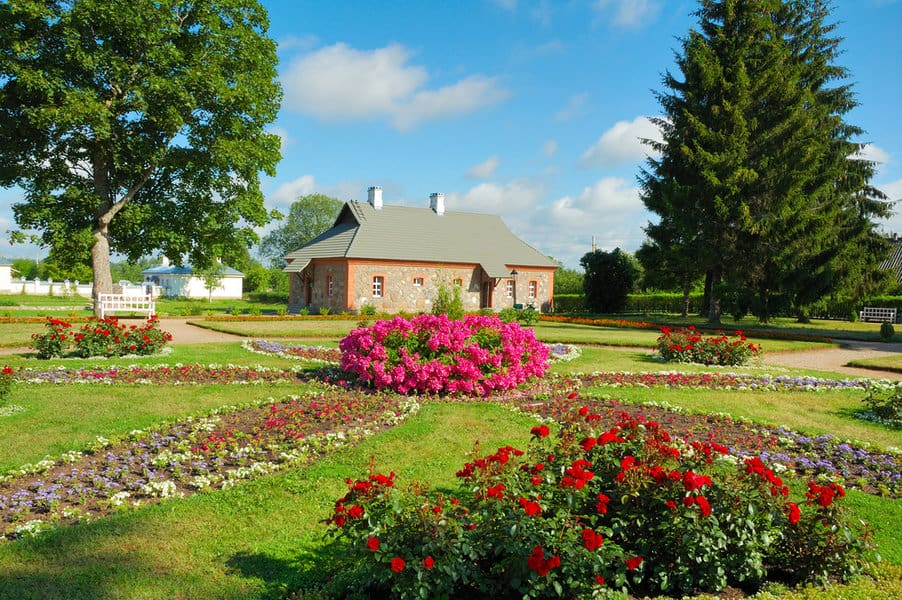Country house with vibrant flower beds and trees