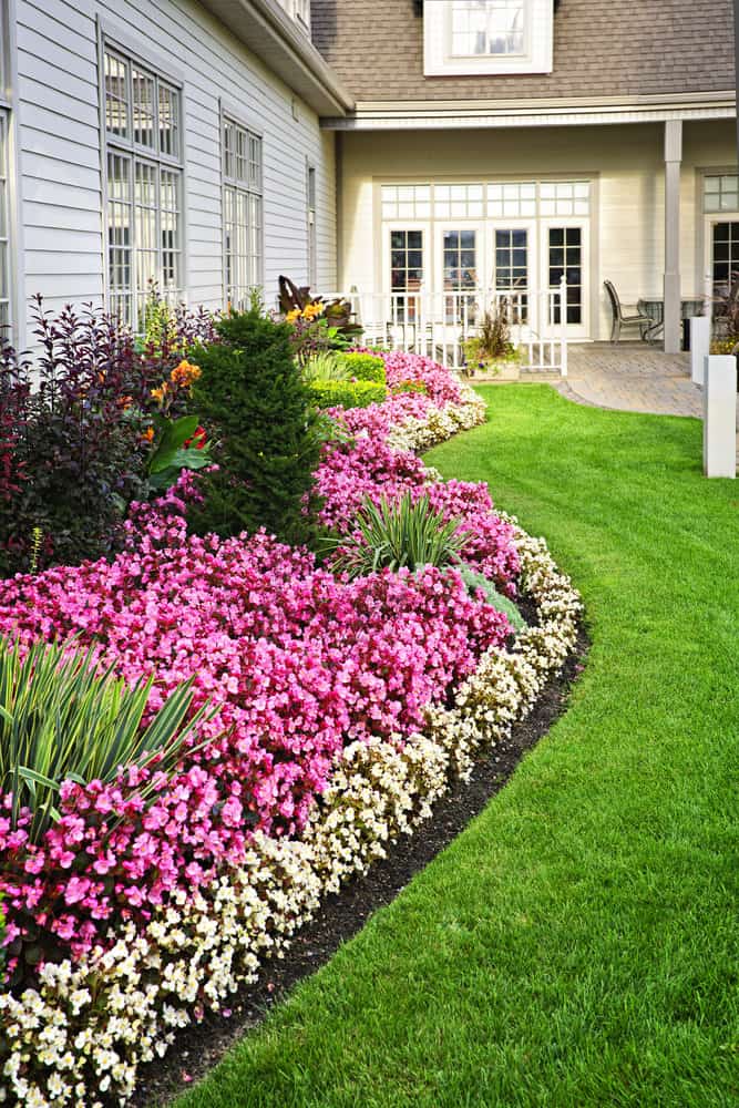 Home with curving flower beds and lush lawn