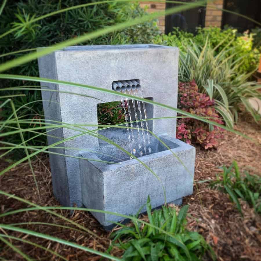 Modern stone water fountain in a lush garden setting