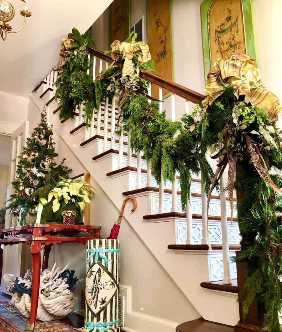 Staircase adorned with garlands and bows, and a decorated Christmas tree beside it